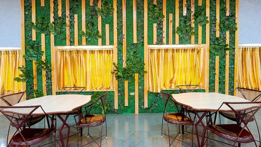 Tables and chairs placed against a green and yellow wall at Greens Inn - Unique Dining in Hyderabad.