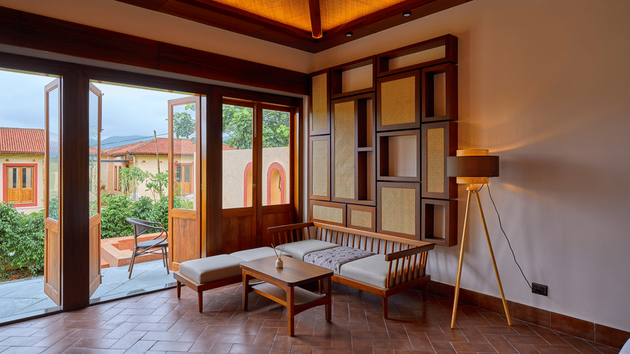 A living area featuring wooden seating, a decorative wall panel, and open doors at Hotel Sonar Bangla, Ajodhya Hills.