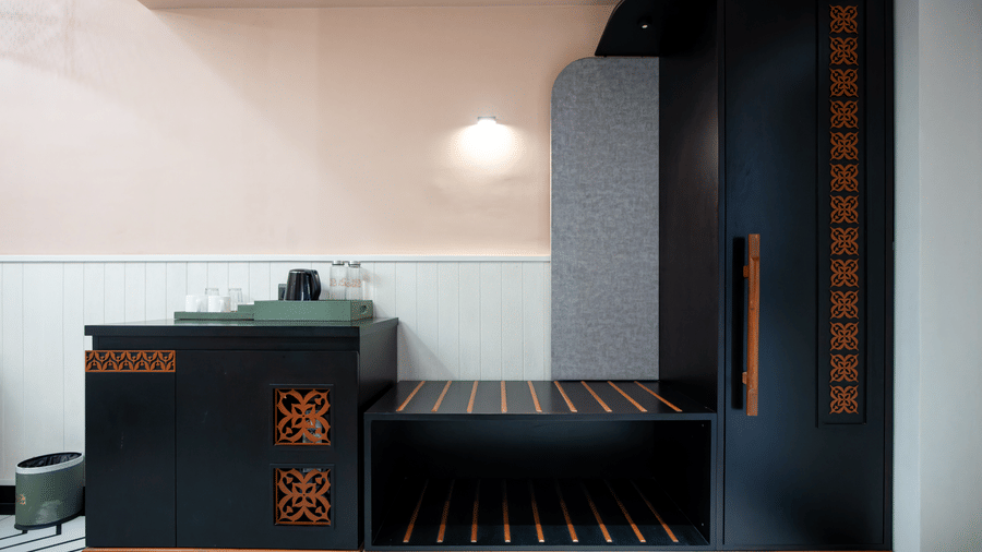 The modern console and wardrobe section inside the Super Deluxe Room with warm pink walls, wooden detailing, and contemporary storage space | Hotel Sonar Bangla, Susunia