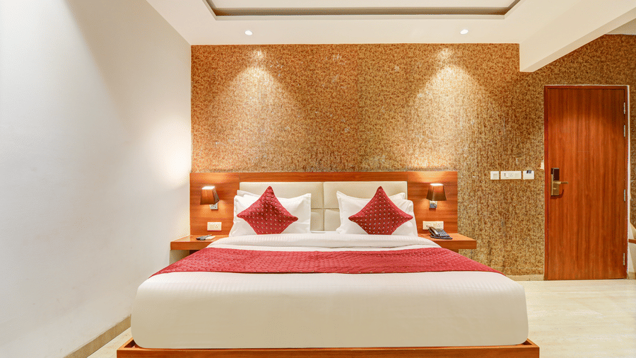 Symmetrical view of a king size bed flanked by wooden nightstands and warm accent lighting - Hotel Velocity