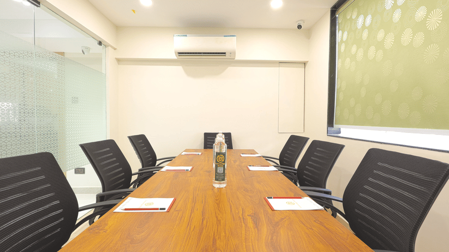A boardroom at Lemonridge by Monday Hotels - KPHB featuring a long wooden table, black mesh chairs, and a glass window wall.