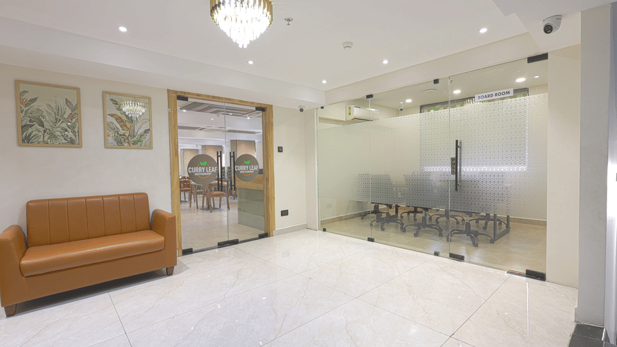 A hallway at Lemonridge by Monday Hotels - KPHB featuring a boardroom entrance, a restaurant doorway, and a sofa with framed pictures above it.