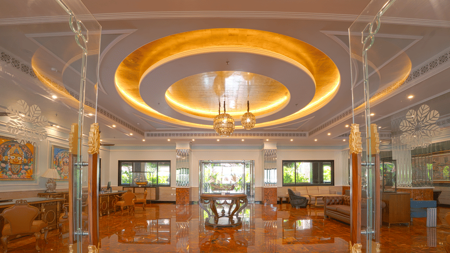 A luxurious indoor space with high reflective flooring, circular illuminated ceiling feature, chandeliers, glass partitions and lounge seating at MAYFAIR Bay Resort, Paradeep.