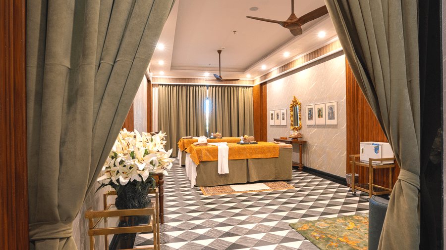 An elegant spa room area decorated with large floral arrangements featuring 2 bed massage beds and a black and white geometric tiled floor at MAYFAIR Bay Resort, Paradeep.
