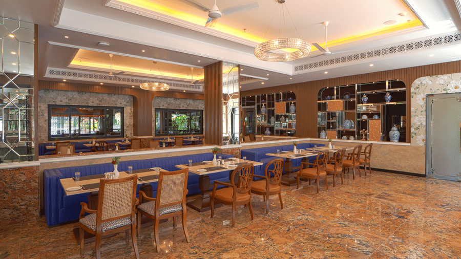 Spacious, brightly lit dining hall with rows of set tables and chairs, marble flooring, and large windows on the far wall at MAYFAIR Bay Resort, Paradeep.