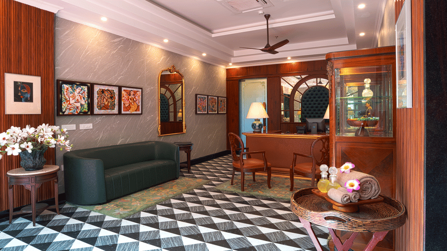A lounge area featuring a dark sofa, decorative mirror, artwork, and a distinctive black and white tiled floor at MAYFAIR Bay Resort, Paradeep.