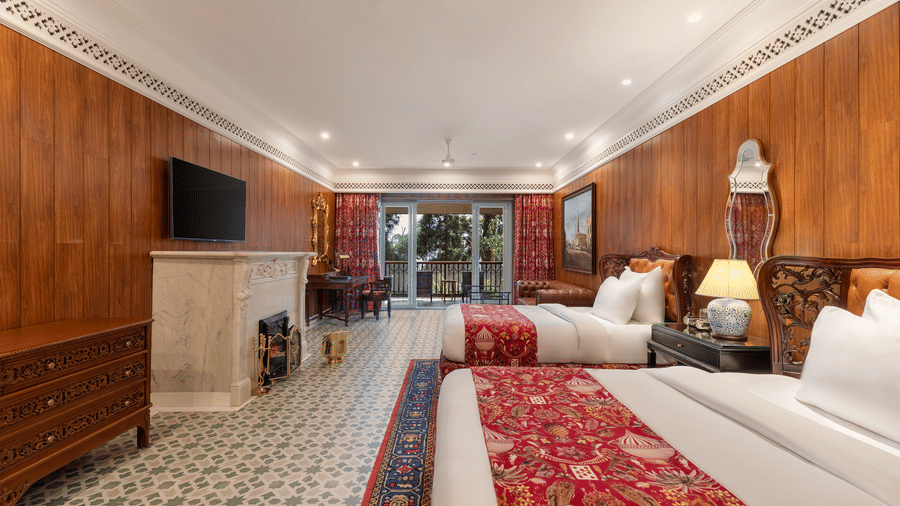 Elegant suite bedroom with twin beds, fireplace, and wood-panelled walls at Mayfair Manor, Jungpana.