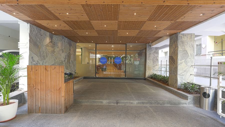 A covered driveway of Monday Hotels HITEC City, Hyderabad's entrance with glass walls.