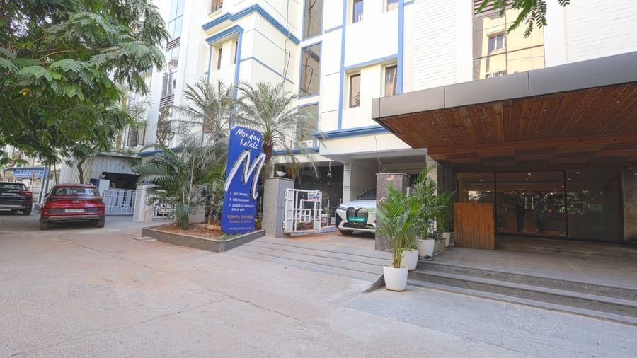 The front entrance of the hotel with a driveway and parked vehicles – Monday Hotels HITEC City, Hyderabad