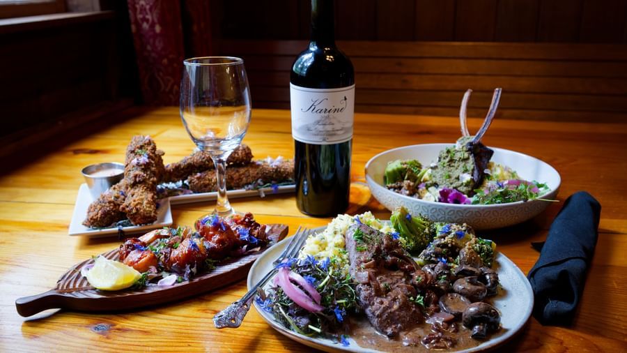 Elegant dinner setting with wine, salad, grilled meat, and pasta in a cozy dining room at Narrow Gauge Inn.