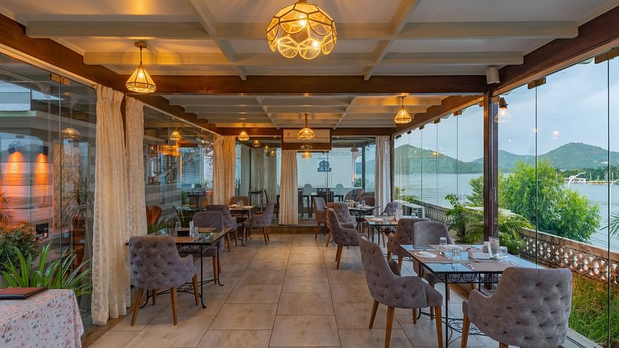 Restaurant area at Panna Vilas Palace showcases a four-seater table with wooden chairs, enhanced by warm lighting and the presence of potted plants | Panna Vilas Udaipur