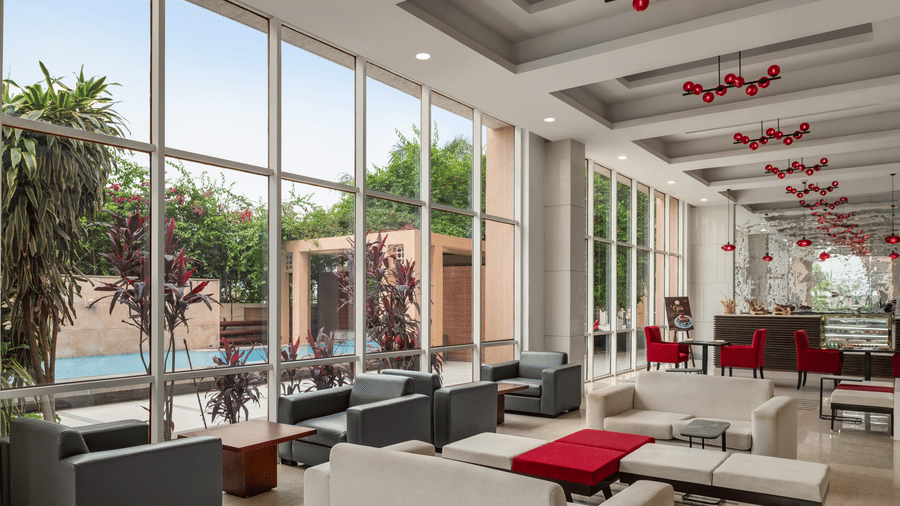 The expansive lobby area at Ramada by Wyndham Bodh Gaya Mahabodhi features comfortable seating arrangements near the glass windows.