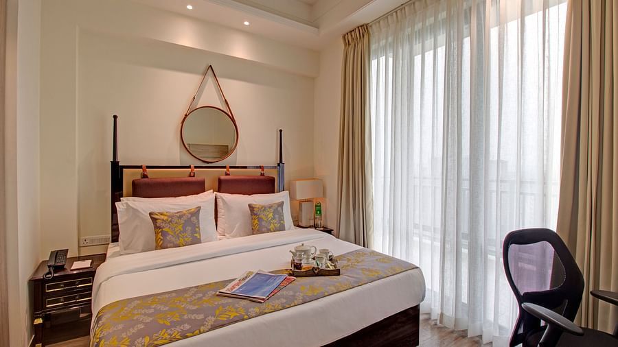 a king bed with side tables and a study desk opposite the bed inside Deluxe Suite at Rhythm Gurugram
