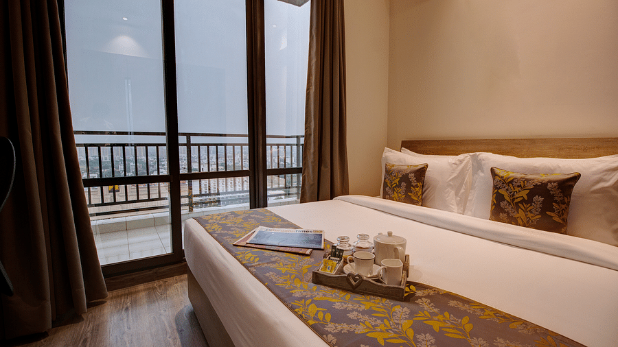 a king bed with pillows and bed runner inside the Two bedroom Executive Suite - Rhythm Gurugram