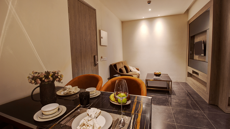 a dining table with sofas and a coffee table in the background inside the living room of Two bedroom Executive Suite - Rhythm Gurugram