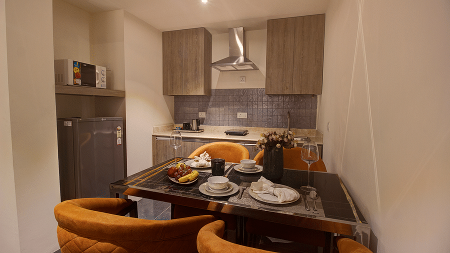 A dining table with a kitchen in the background of Two bedroom Executive Suite - Rhythm Gurugram
