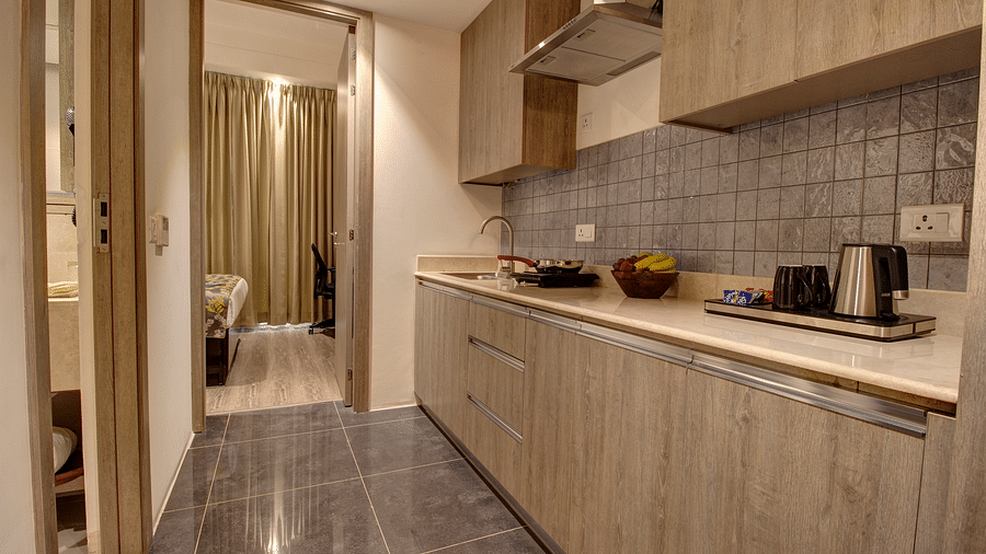 Overview of the Kitchenette with an electric stove and a kettle kept on the counter inside the deluxe room - Rhythm Gurugram