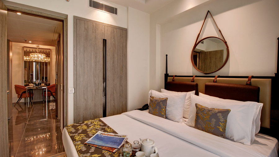 The Deluxe Suite with a king size bed, elegant decor, and an attached living and dining area for business travellers.
