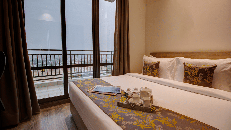 A king size bed with pillows and bed runner inside the Executive Suite at Rhythm Gurugram.