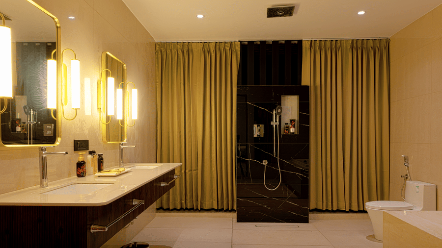 Bathroom at SUKAVI featuring a double floating vanity, two square mirrors with vertical lights on each side, and a gold curtain visible in the background.