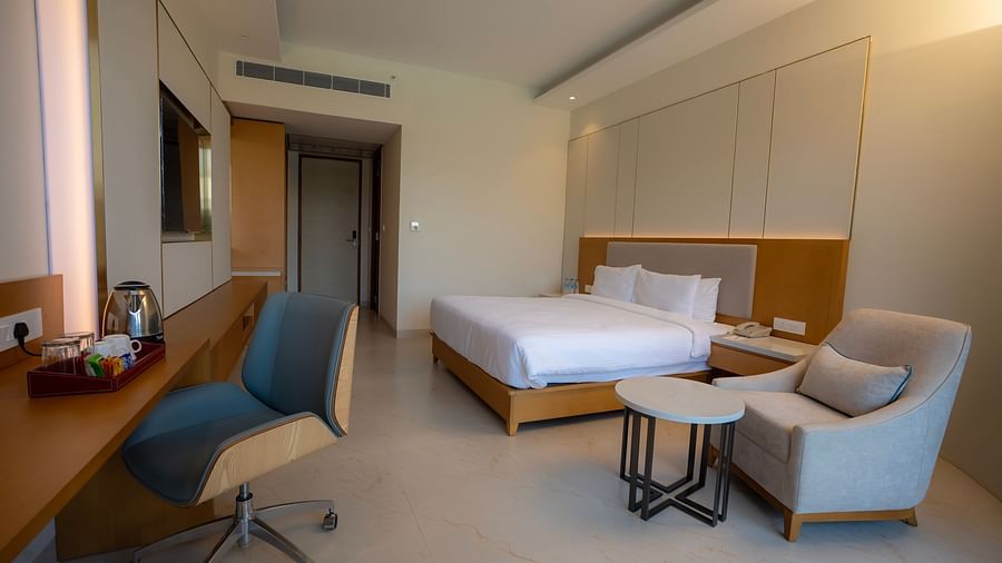 Interior of the Pool View Bliss featuring modern furnishings along with a double bed and an armchair beside it with a table at The Shore, Trishvam.