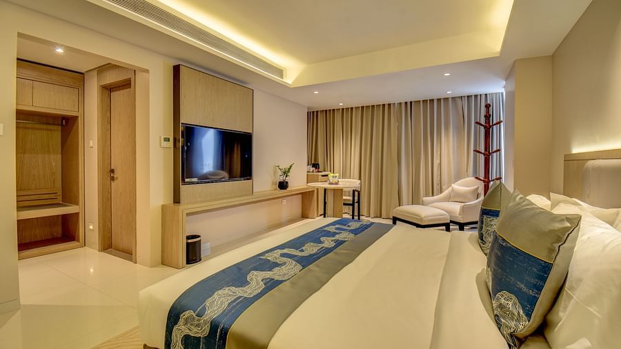Close up of Deluxe King room at The SSK Solitaire Boutique Hotel & Spa, Gangapur Road - Nashik featuring a king size  bed, two armchairs, a small table, and a work desk with a chair.