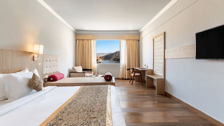 A close-up shot of a bed with a patterned runner on it, opposote to it is a tv mounted on the wall -  Via Lakhela Resort & Spa 