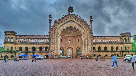A wide shot of a large, intricate, old palace or building with a courtyard in front.