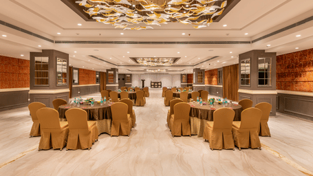 Back shot of the Chancellor hall featuring the main stage area in the far end of the hall, with brightly lit interiors and wooden panelling on the walls - Skkylight Lords Inn, Nanded