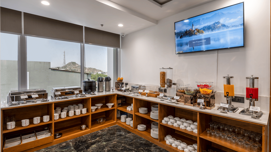 A BCR buffet area featuring a selection of breakfast foods, neat and tidy worktops, TV on the ceiling and a glass windows