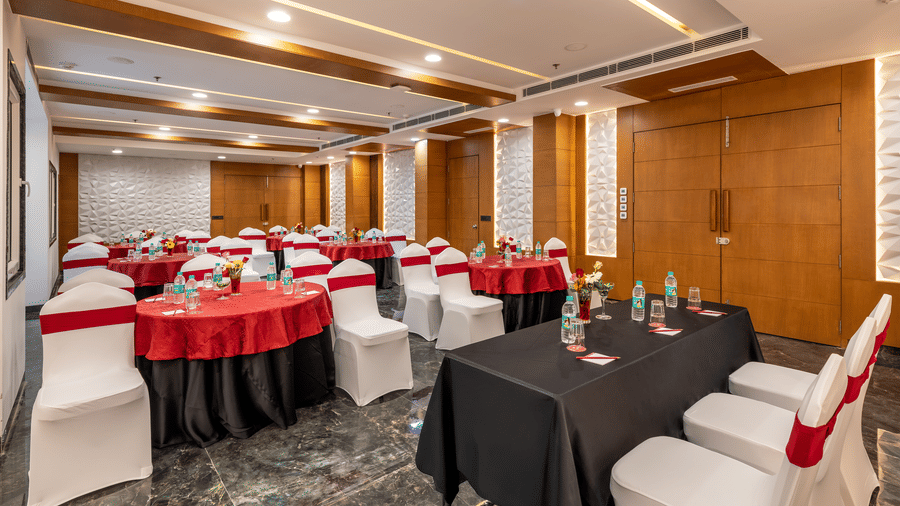 Banquet sitting setup with round and rectangular tables, red and white chair covers, and wood-paneled walls.