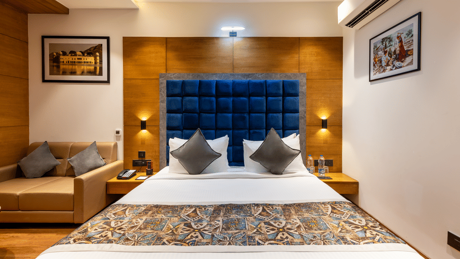 The best hotel in Sumerpur Rajasthan, Lords hotel, featuring its executive bedroom with a large bed, royal blue headboard, ambient lighting with sofas in the corner.