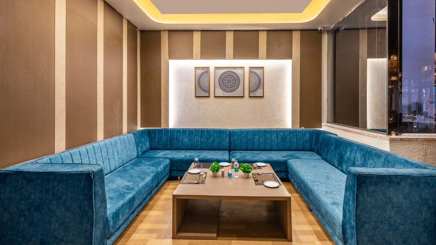 Lounge seating area at Lords Inn Sangam, Bhopal featuring a plush blue sofa, wooden coffee table, and framed wall art.