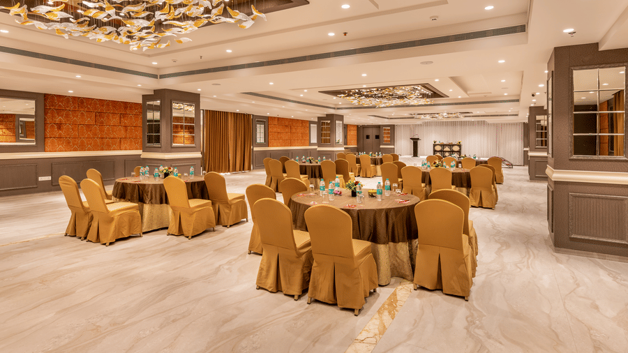 Full view of the Chancellor hall featuring the chairs and table arranged in a round-table configuration for an event, facing the stage area with a podium - Skkylight Lords Inn, Nanded