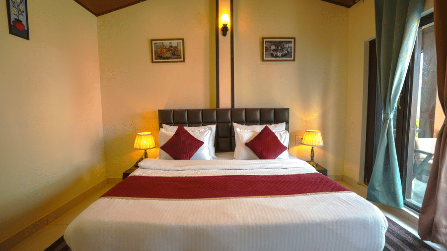 A room with wall hangings, lamps etc adding charm to the king size bed with cushions