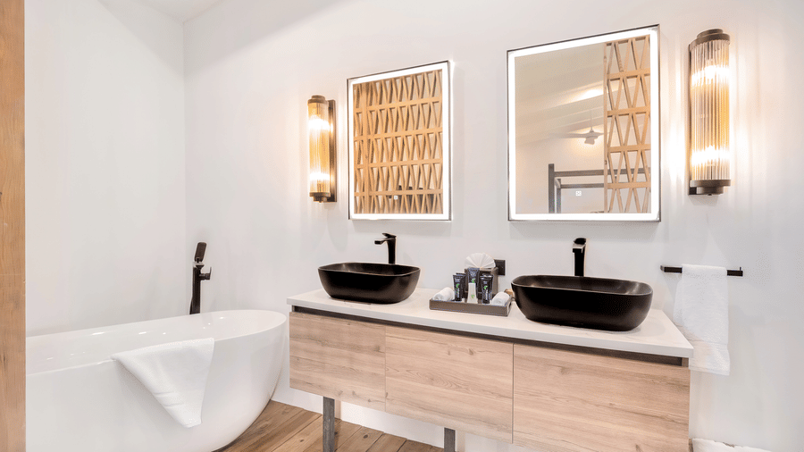 A bathroom at the Tamarind Hills Resort and Villas, Antigua, with two sinks, two mirrors, a bathtub and amenities.