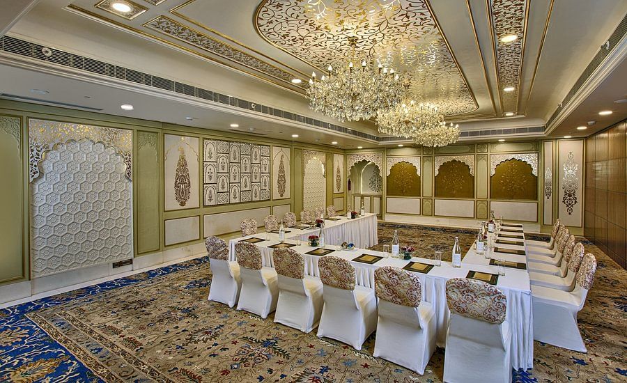 Elegant meeting room with a U-shaped table, ornate ceiling, chandeliers, and patterned carpet - Heritage Village Resorts & Spa.