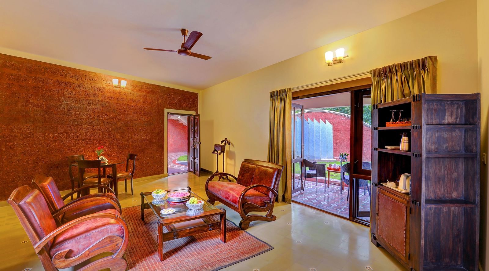 An image of a seating room with many sofas, centre tables, and a cupboard - Hoysala Village Resort, Hassan