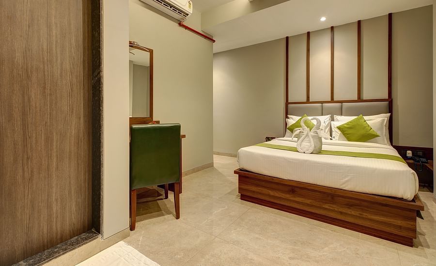 alt-text A double bed with a side table next to it inside Classic AC Room - Fortune House, Magarpatta