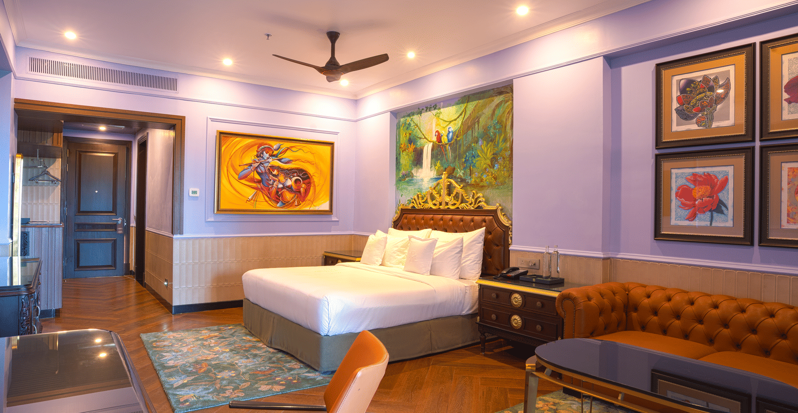 A room with a king size bed, seating area, and vibrant, large abstract paintings decorating the wall space at MAYFAIR Bay Resort, Paradeep.