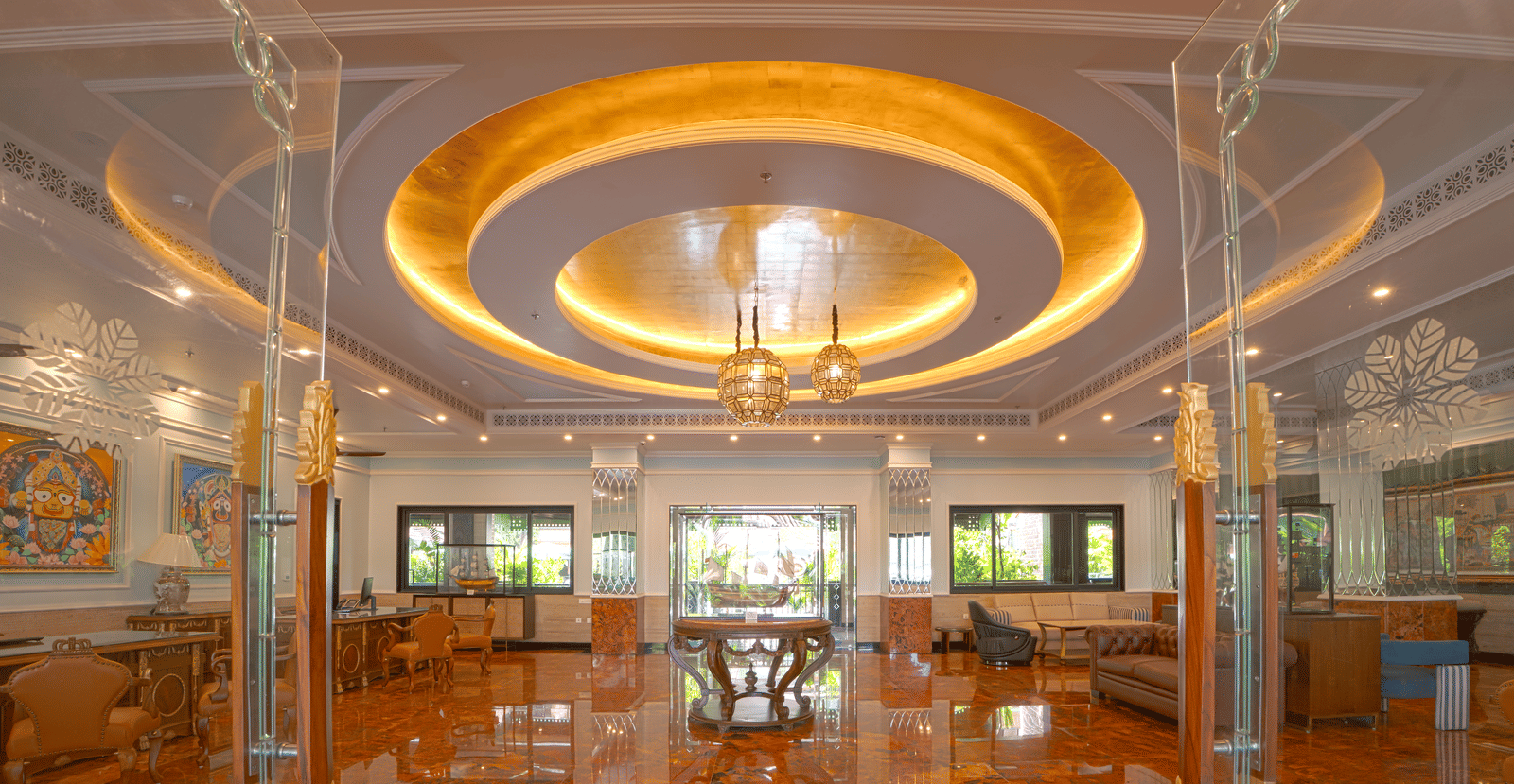A luxurious indoor space with high reflective flooring, circular illuminated ceiling feature, chandeliers, glass partitions and lounge seating at MAYFAIR Bay Resort, Paradeep.