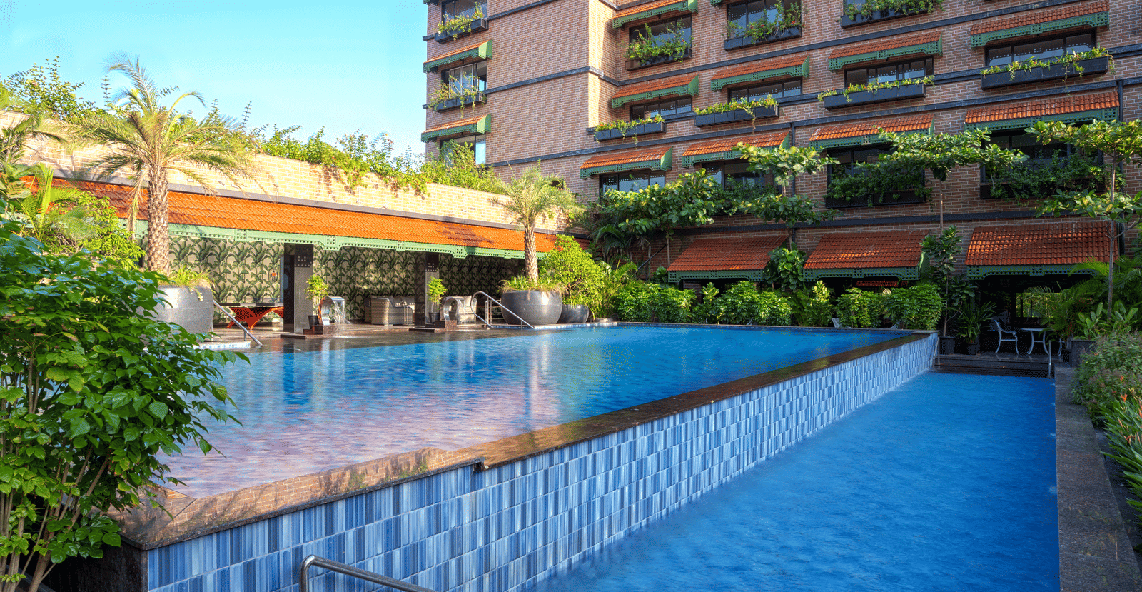 Exterior view of MAYFAIR Bay Resort, Paradeep's building with dark cladding, overlooking a rectangular swimming pool.