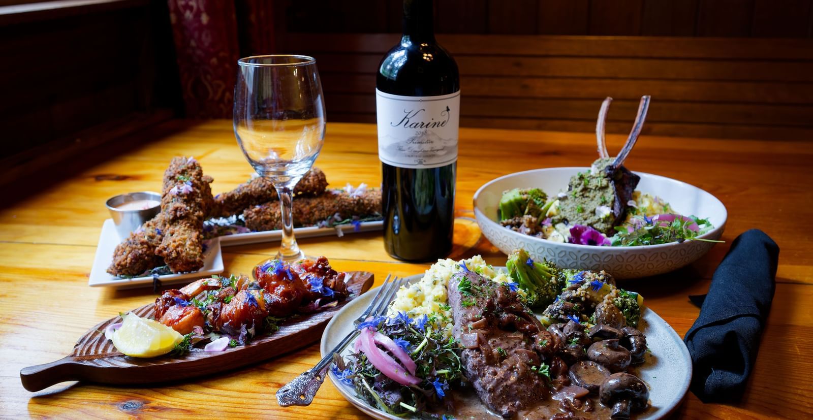 Elegant dinner setting with wine, salad, grilled meat, and pasta in a cozy dining room at Narrow Gauge Inn.