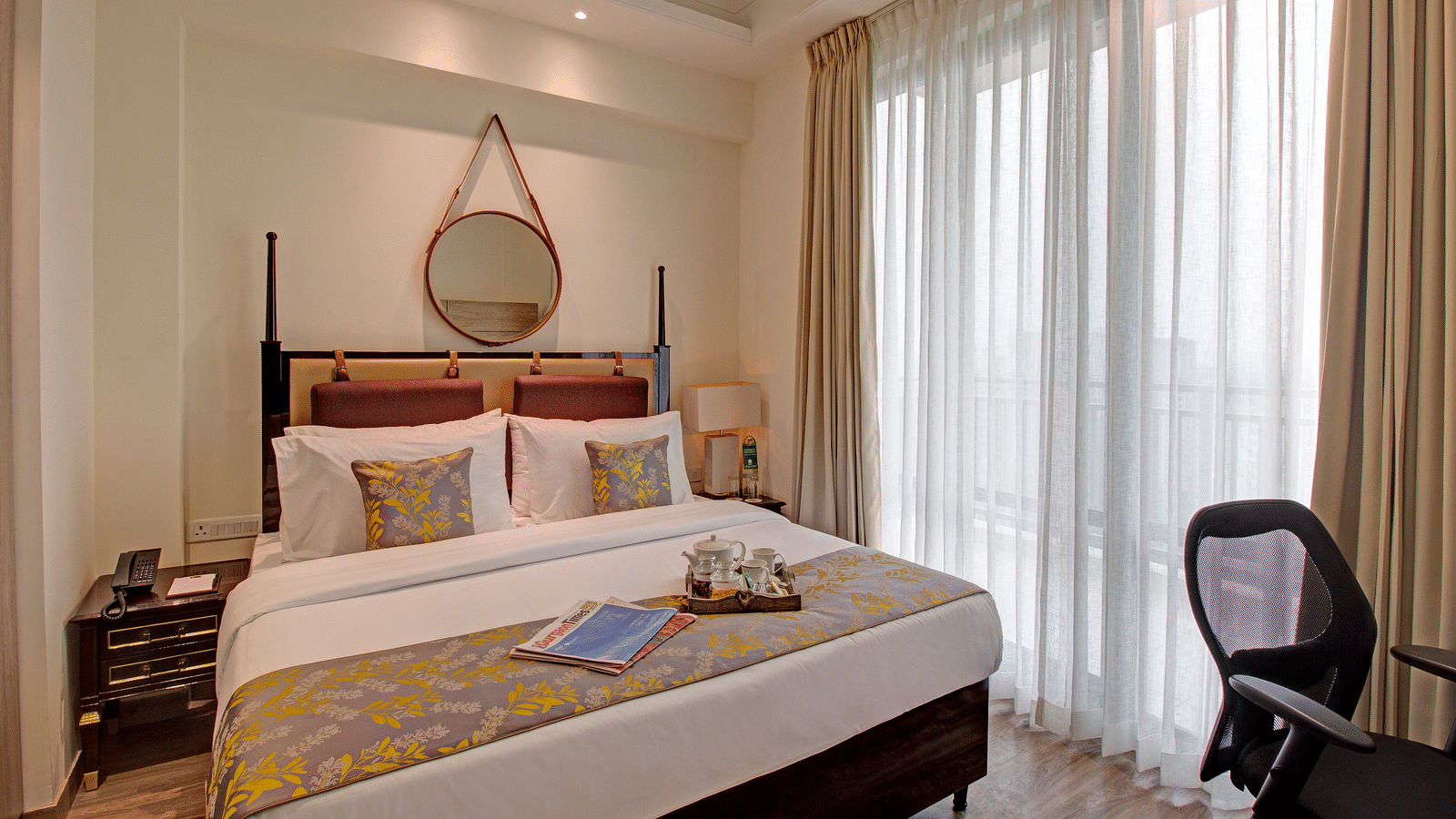 a king bed with side tables and a study desk opposite the bed inside Deluxe Suite at Rhythm Gurugram