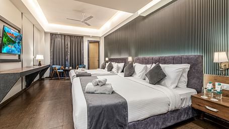 A shot of a room with two beds, bed side tables, a flat screen TV, and other room amenities - DLS Ganga Bliss, Haridwar