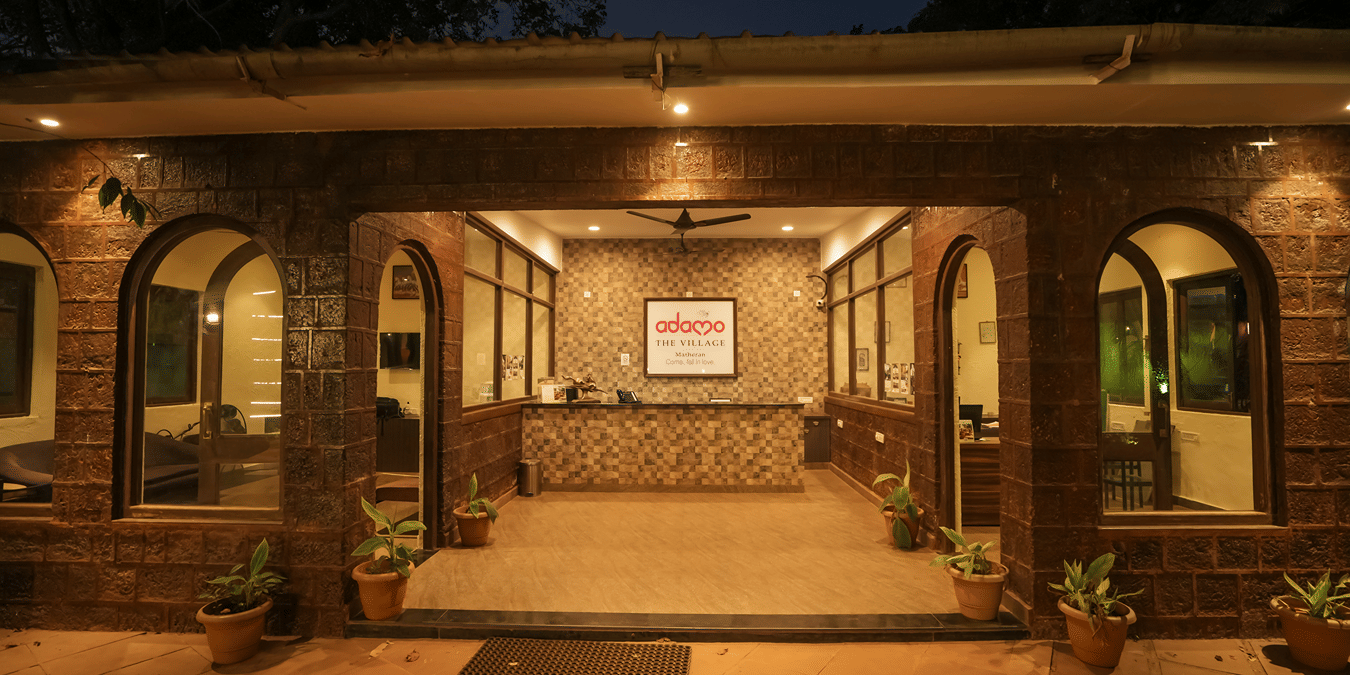 A brightly lit stone facade resort reception entrance showing an indoor front desk at night.