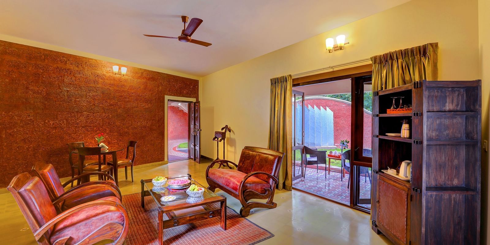 An image of a seating room with many sofas, centre tables, and a cupboard - Hoysala Village Resort, Hassan