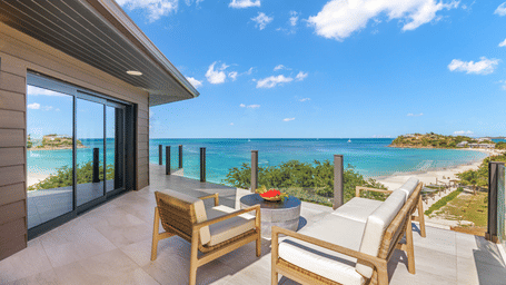Outdoor terrace with cushioned seating and a table overlooking the sea at Ocean 19, Tamarind Hills Resort and Villas.