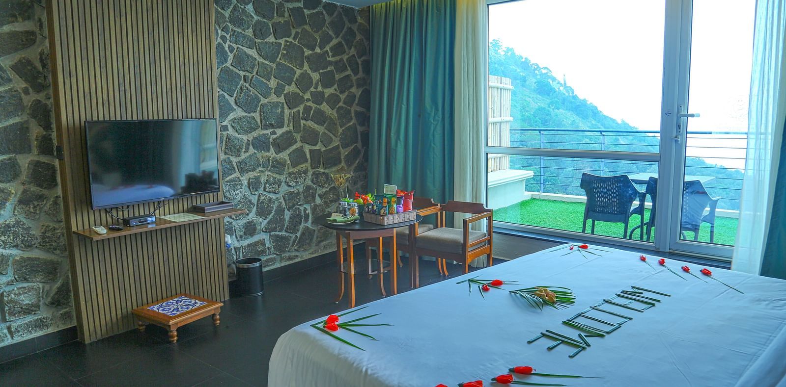 Image of valley view room with king size bed, flat screen TV, an expansive glass door leading to the balcony - An image of a a valley view room with king size bed, bed side table, flat screen TV, wardrobe, air-conditioner, and decorative items - Great Trai