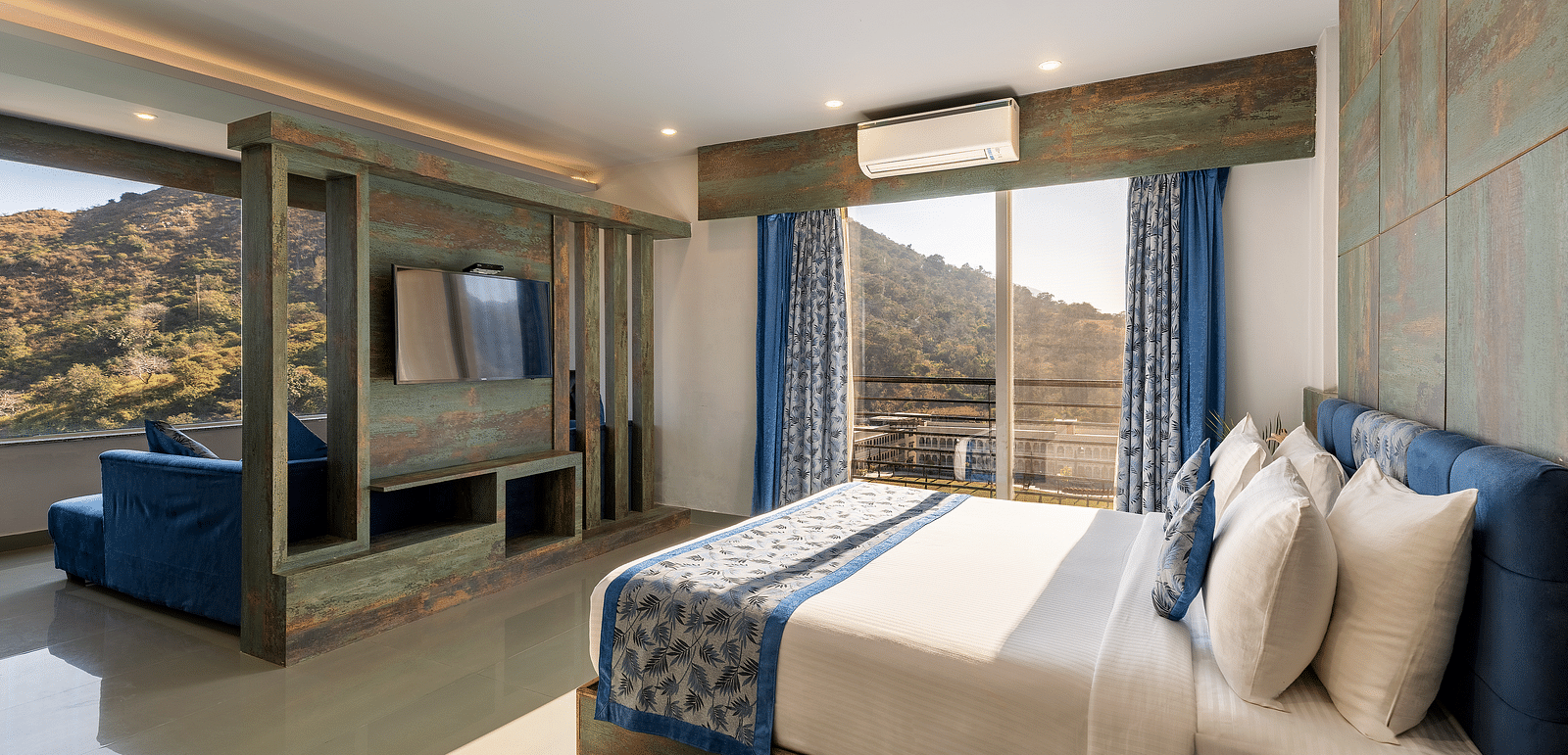 A hotel bedroom with matching runner and curtains and a open view - Via Lakhela Resort & Spa, Kumbhalgarh